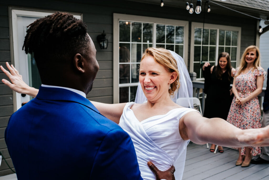 bride holding arms out as she walks up to her groom to do their first dance and she is grinning