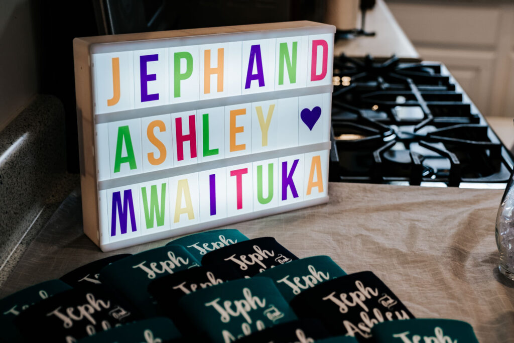 sign that says jeph and ashley mwaituka in multicolored letters and coozies that say Jeph and Ashley
