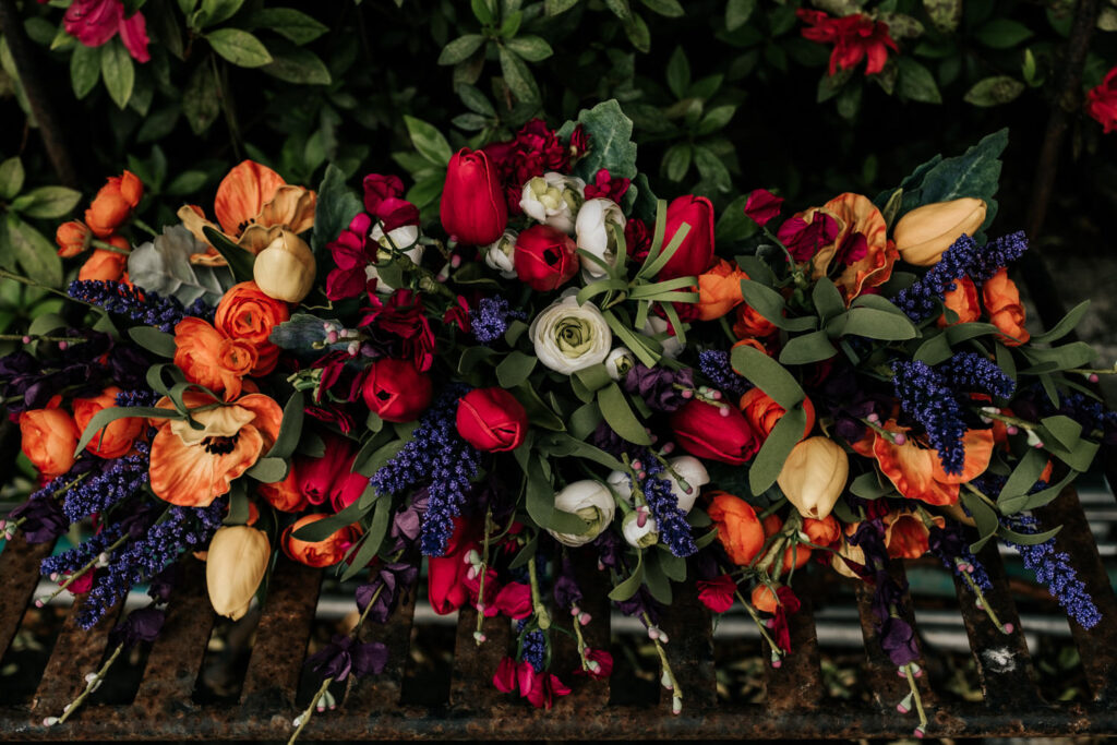 orange red white and green bouquets on a metal bench