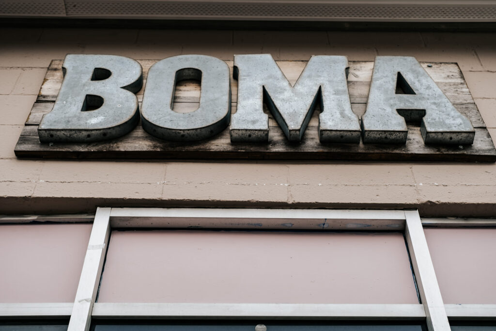 A shop sign that says Boma in silver metal letters
