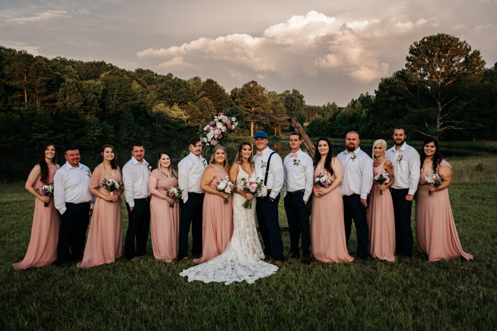 full bridal party with pink dresses and boys wearing navy pants and white shirts