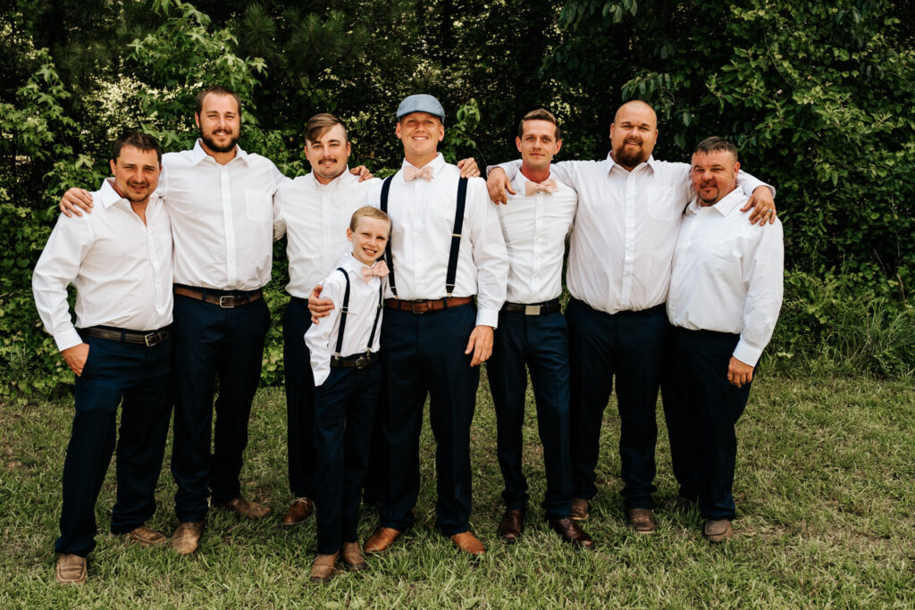 Groom with groomsmen with arms around each other smiling