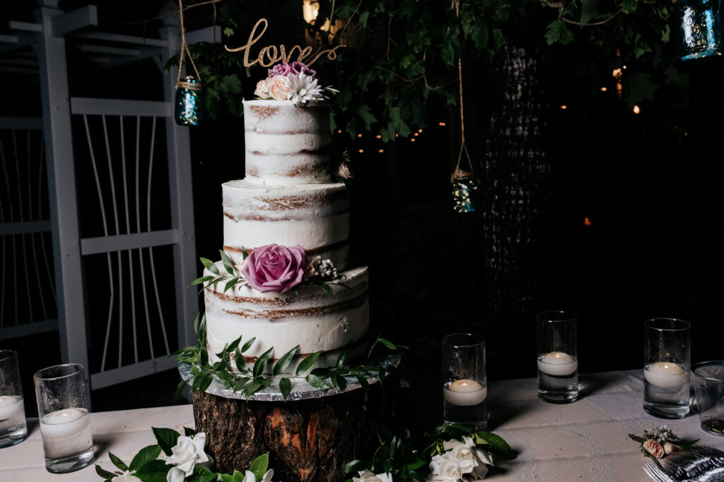 wedding cake with purple flowers and almost naked style icing