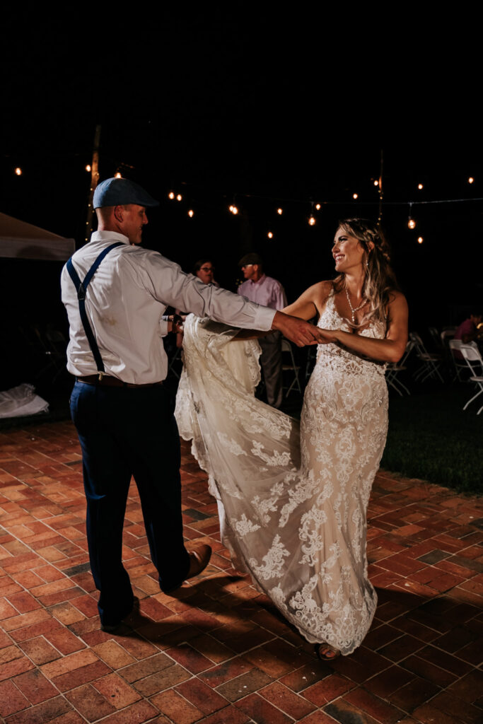 bride and groom doing first dance with hanging lights in background