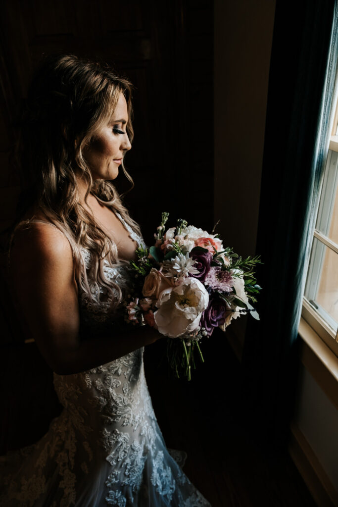 Bride standing in front of window with bouquet