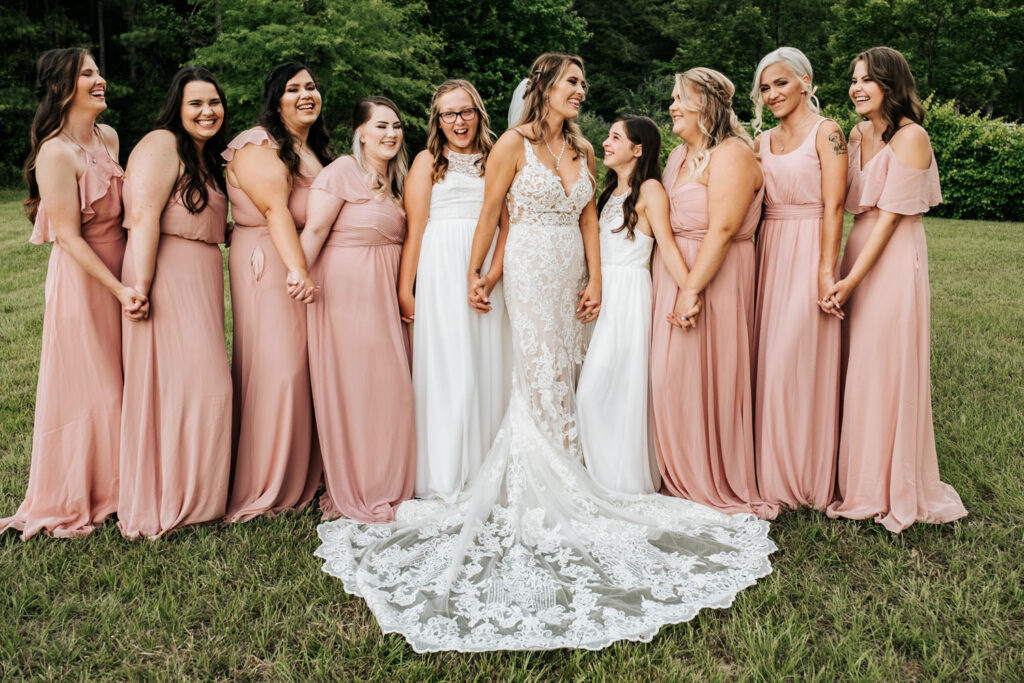 Bride with bridesmaids holding hands and laughing